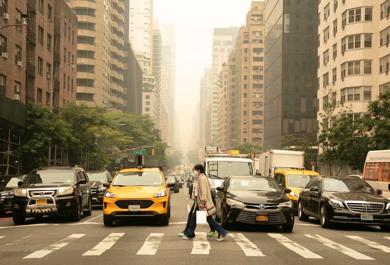 Person crossing the street in NYC under a haze of wildfire smoke